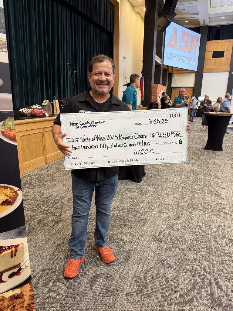 A local business owner holds a $250 People's Choice award check from the Wise County Chamber of Commerce Taste of Wise 2025 event